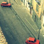 Geometrie vive nel Centro Storico: strade, case e due macchine rosse