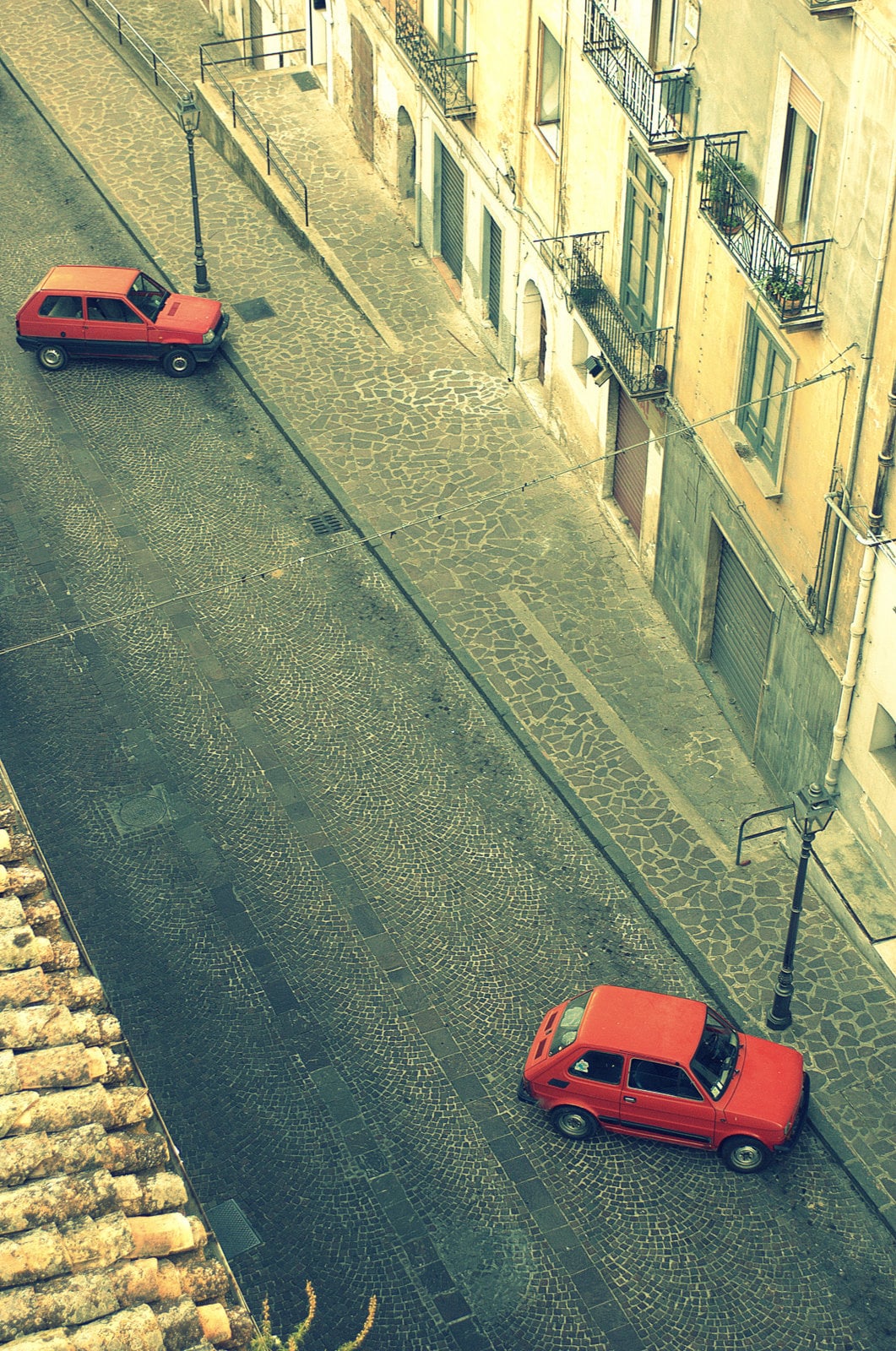 Geometrie vive nel Centro Storico: strade, case e due macchine rosse