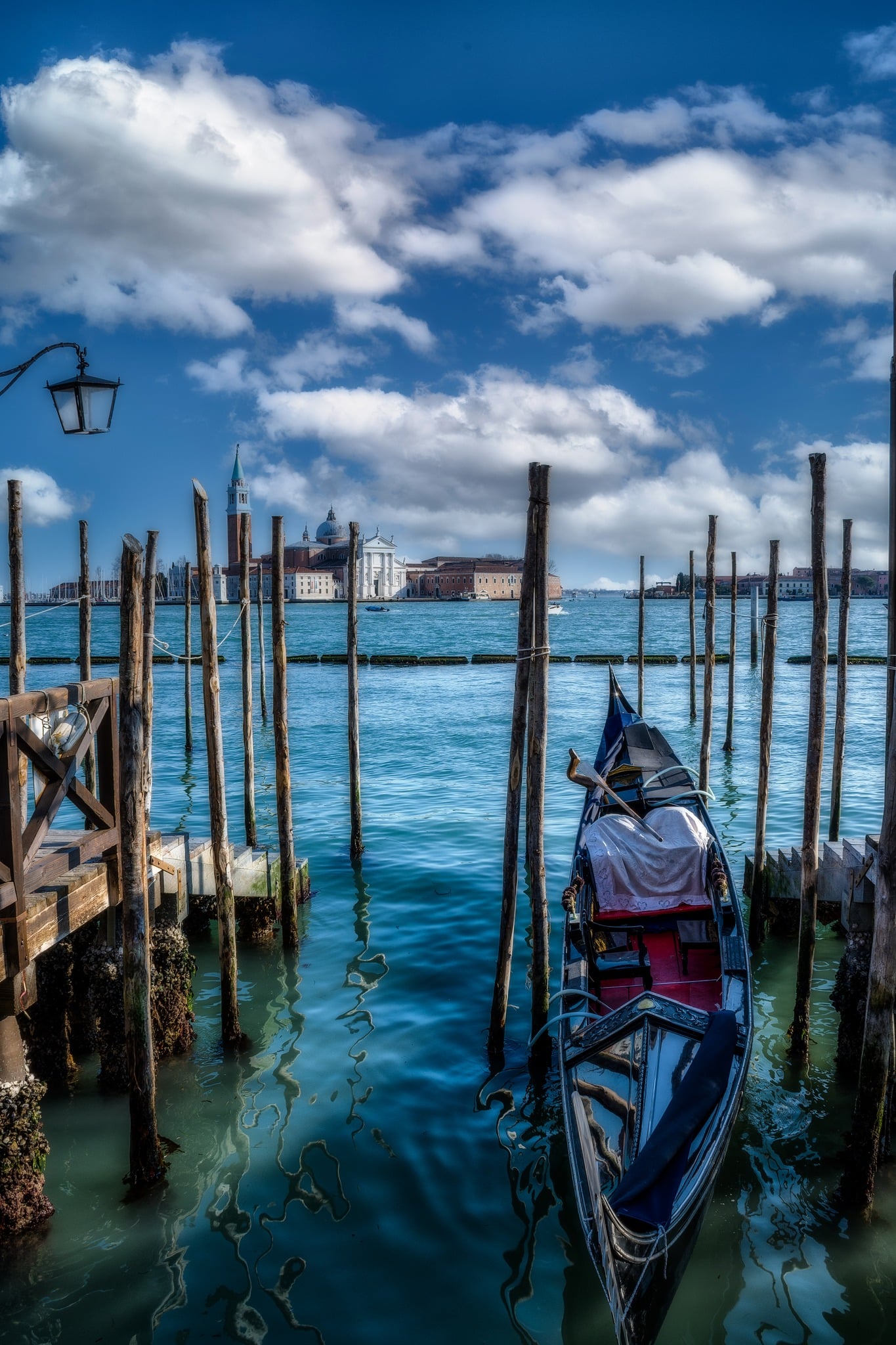 Venezia tra cielo terso e riflessi: dialogo tra pali e barca nel porto del centro storico