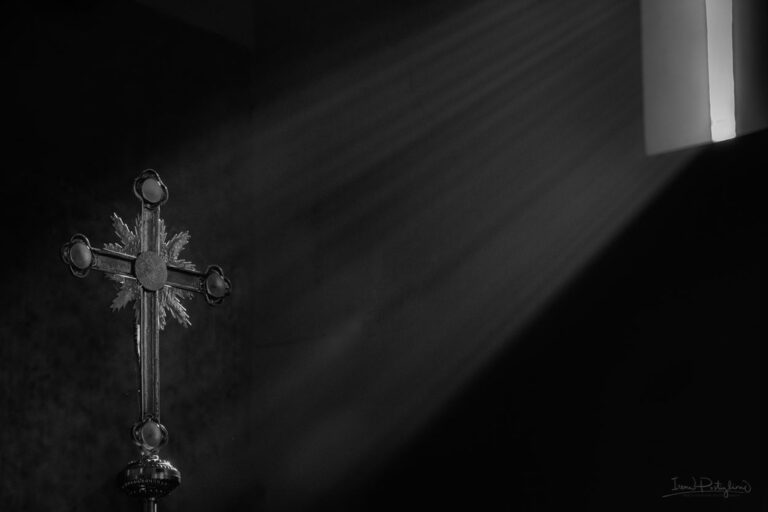 Croce dorata in bianco e nero: silenzio e luce diagonale