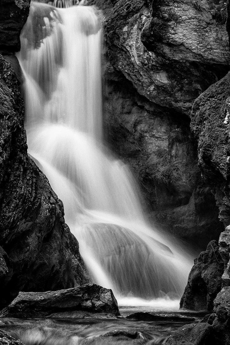 Cascata al centro-sinistra: forza dell’acqua e struttura rocciosa in BW