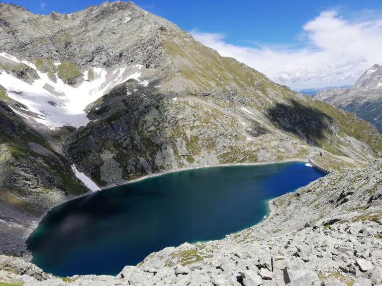 Paesaggio d’alta quota: roccia, neve e lago in una lettura di profondità e luce