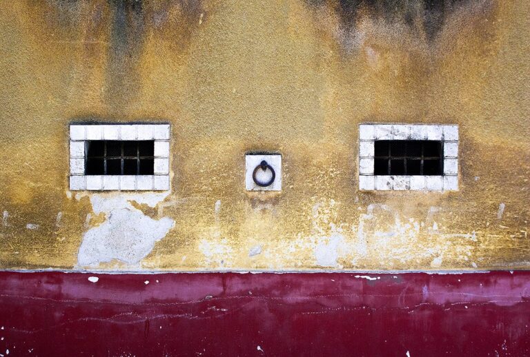 Parete giallo-ocra, anello al centro: nitido equilibrio tra texture e linea