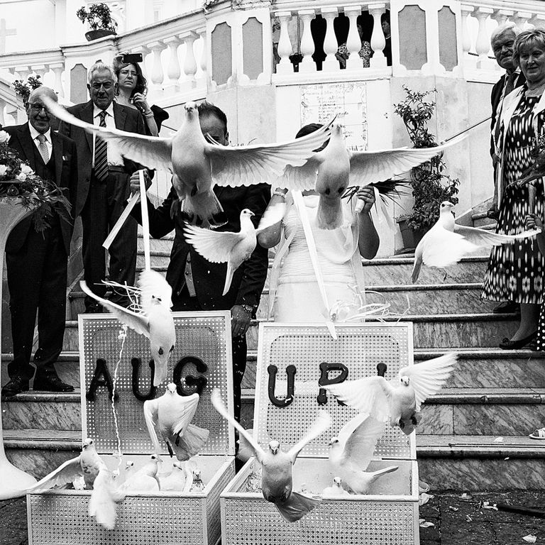 Auguri sospesi: colombe, scale e contrasti in nero e bianco per una lettura teatrale del gesto pubblico