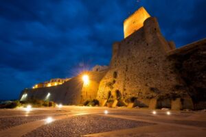 Castello al tramonto: dominio della pietra contro il cielo profondo e luci arieggiate
