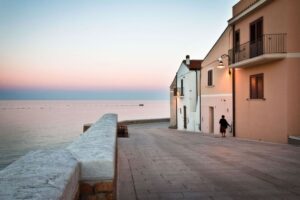Crepuscolo sul mare: equilibrio tra luce, architetture e figura solitaria