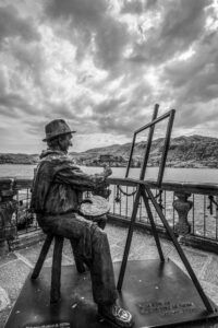 Orta San Giulio in bianco e nero: statua osservatrice tra lago e borgo